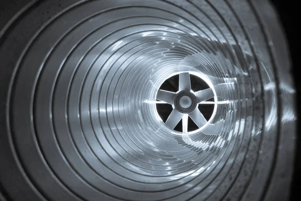 Arka plandaki egzoz vantilatöründeki galvanize çelik hava kanalının içerisinden yakın çekim görüntüsü Bokeh etkisi ile ön ve arka plan bulanıklaşır.