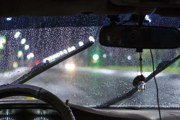 güzel araba ile açık, bir fırtına ve yağmur gece şehirde sırasında cam temiz ön cam su damlaları. ön ve arka arka plan bulanık