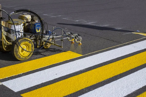 Yol işçileri şehrin asfalt yolundaki yaya geçidini boyamak için sıcak eritilmiş karalama makineleri kullanıyorlar..