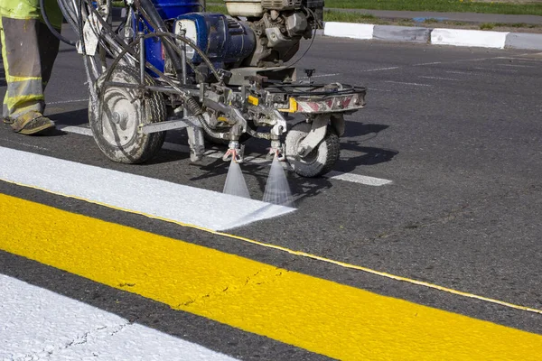 Yol işçileri şehrin asfalt yolundaki yaya geçidini boyamak için sıcak eritilmiş karalama makineleri kullanıyorlar..