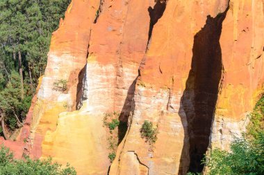 Reddish rock formations made of ocher near Rousillon village, Provence, France clipart