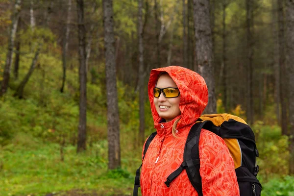 Glimlachende vrouwelijke reiziger in het herfstbos — Stockfoto