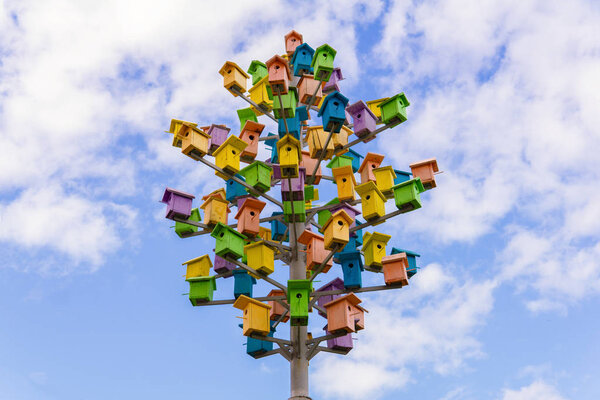 art object tree of birdhouses against the sky
