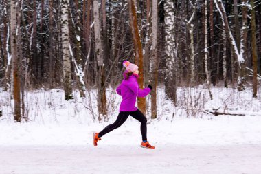 Genç bir kadın kış günü koşuyor.