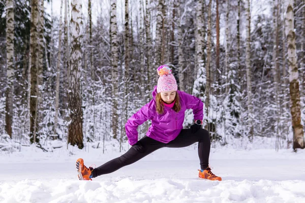 Mujer joven calentándose antes de correr en un parque de invierno —  Fotos de Stock