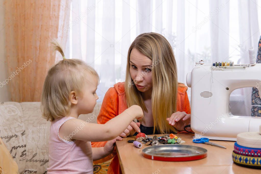 seamstress woman interrupted work and plays with little daughter