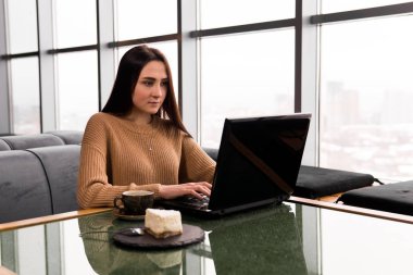 Bir kafede dizüstü bilgisayarda çalışan genç bir kadın.