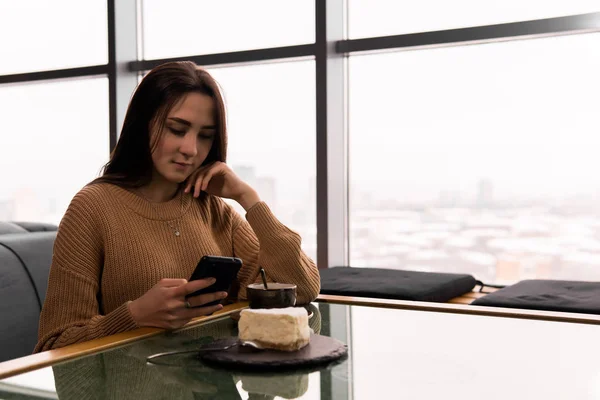 Mujer joven marca un número en el teléfono mientras está sentado en un café — Foto de Stock