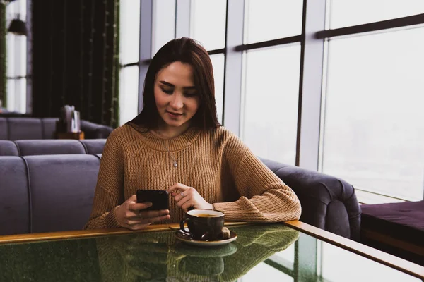 Mujer joven marca un número en el teléfono mientras está sentado en un café — Foto de Stock