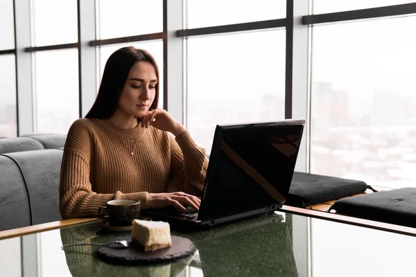 Giovane donna che lavora su un computer portatile in una caffetteria — Foto Stock