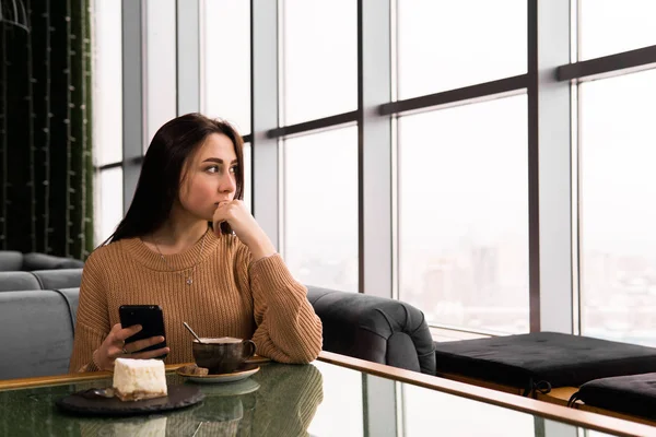 Adolescente en una cafetería mira por la ventana sosteniendo un ph — Foto de Stock