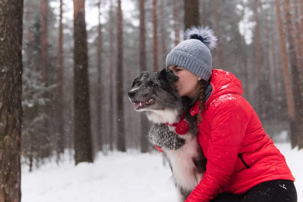 Young woman kisses her dog in a winter park — ストック写真