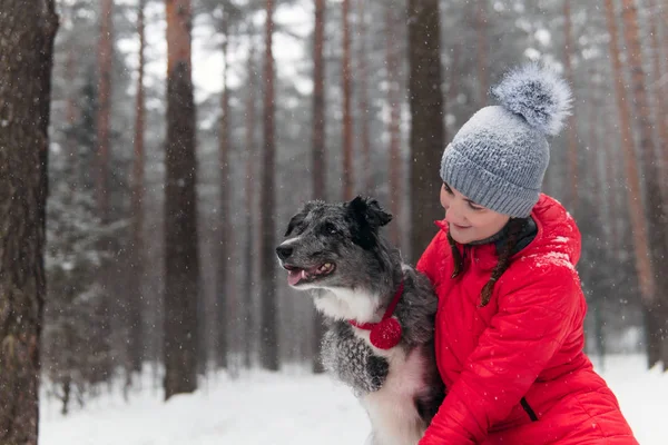 Young woman wits her dog in a winter forest — ストック写真