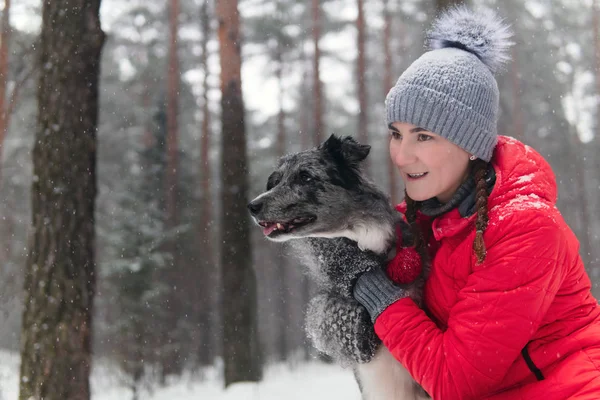 Young woman wits her dog in a winter park — ストック写真