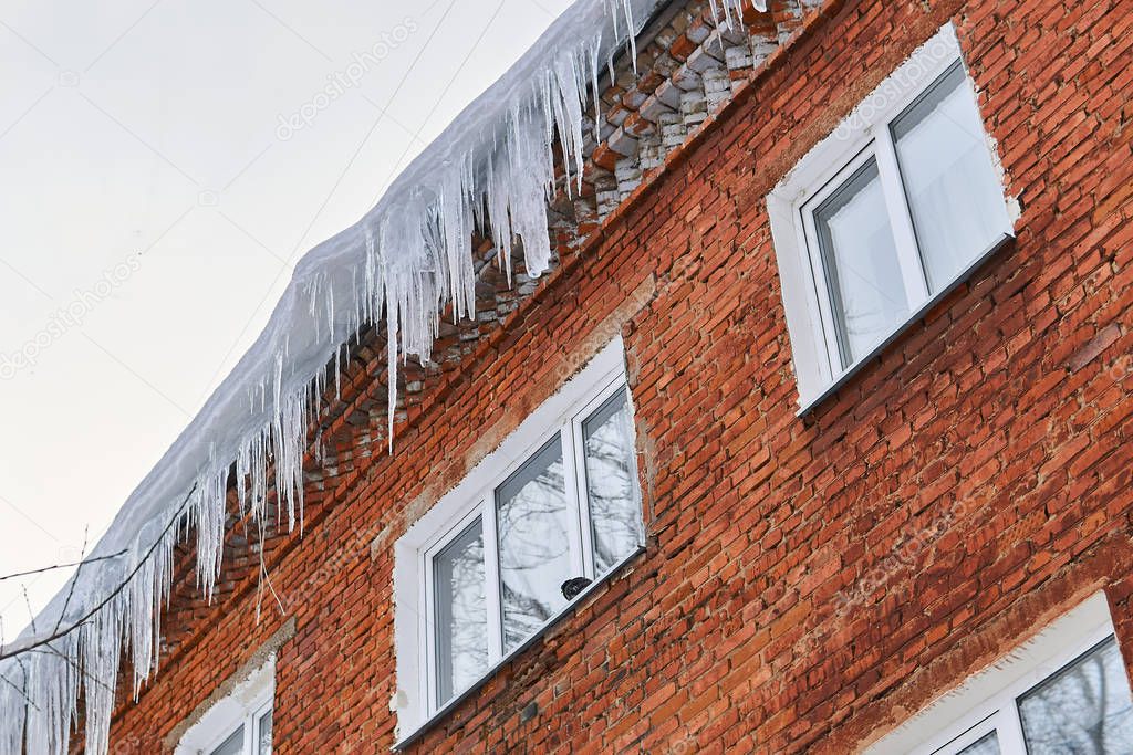 icicles on the roof of a brick house