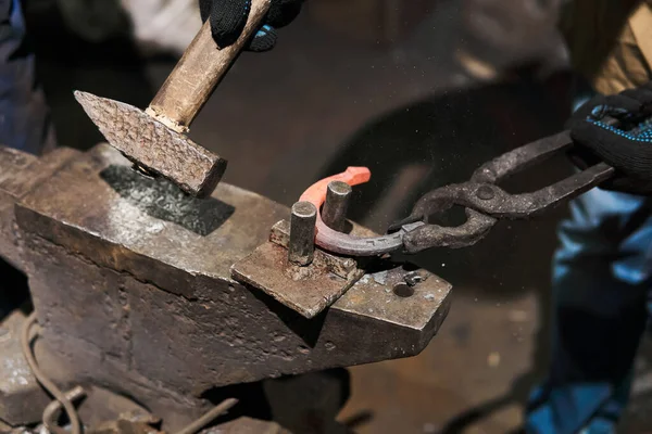 blacksmith forges a horseshoe, close-up