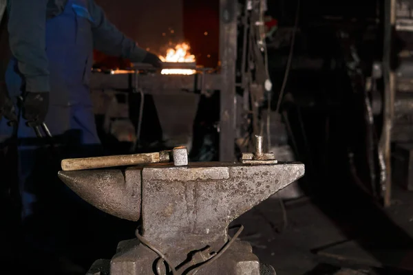 the hammer lies on the anvil in the forge while the blacksmith w