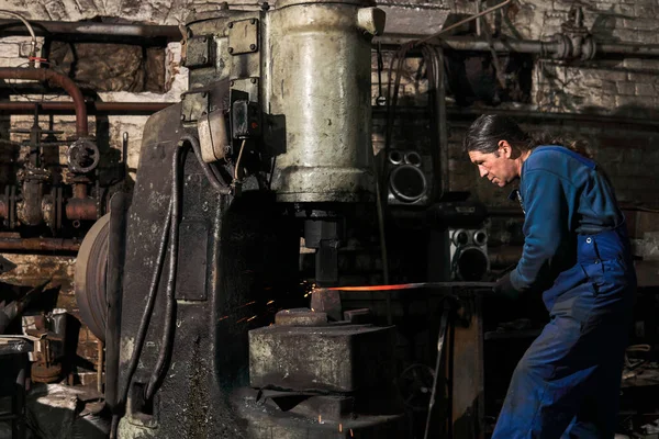 Blacksmith processes a hot workpiece with a power hammer — Stock Photo, Image
