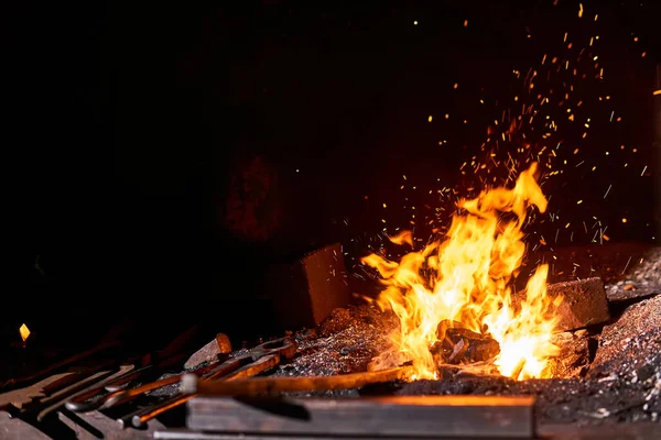 Ковальська піч з палаючим вогнем та інструментами для кування, що лежать — стокове фото