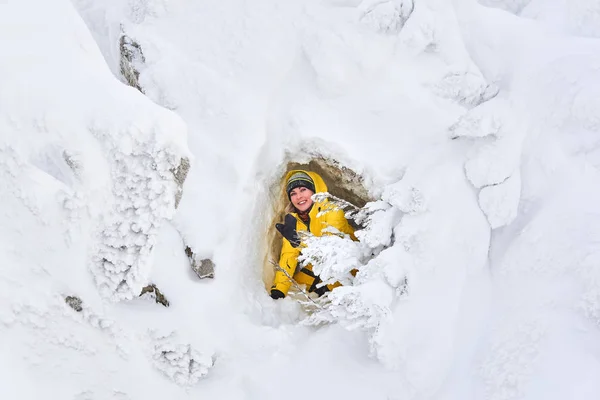 Reisende posiert in einer natürlichen Höhle in einem schneebedeckten Felsen — Stockfoto