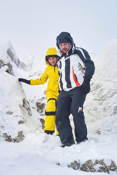 Mann und Frau steigen vom schneebedeckten Gipfel des Berges hinab — Stockfoto
