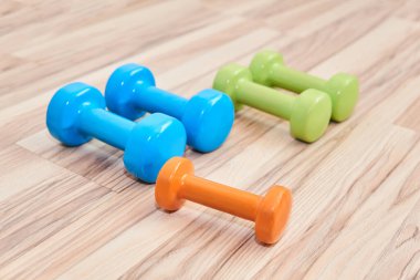 İki çift ve bir çift daha - farklı ağırlıkta ve renkte çeşitli kauçuk halterler yere yatar.