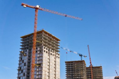 Gökyüzüne karşı kule vinçleri olan çok katlı bina blokları.