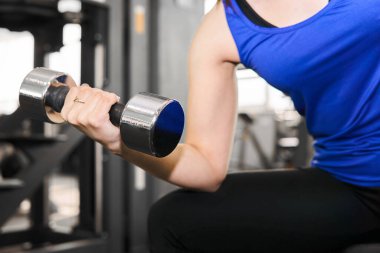 Spor salonunda bisepsler için halter egzersizi yapan bir kadının eli.
