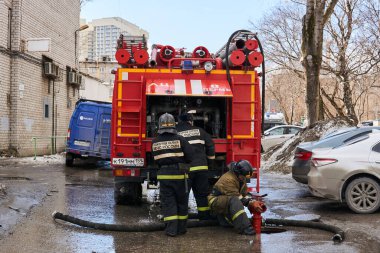 Perm, Rusya - 20 Mart 2020: İtfaiyeciler itfaiye deposunu doldurmak için yeraltı yangın musluğu kullanıyorlar.