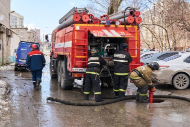 Perm, Rusya - 20 Mart 2020: İtfaiyeciler itfaiye deposunu doldurmak için yeraltı yangın musluğu kullanıyorlar.