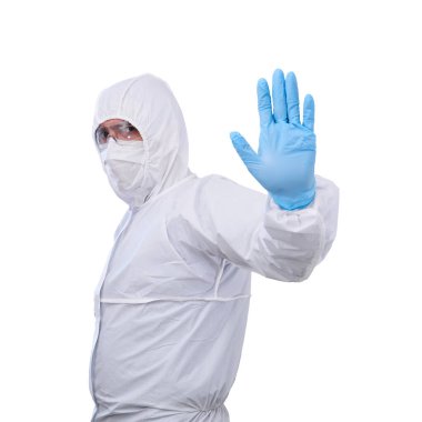 Tek kullanımlık anti-bakteriyel izolasyon giysisindeki erkek epidemiyoloji uzmanı bir eli beyaz arka planda izole edilmiş yasaklayıcı bir jest gösteriyor.