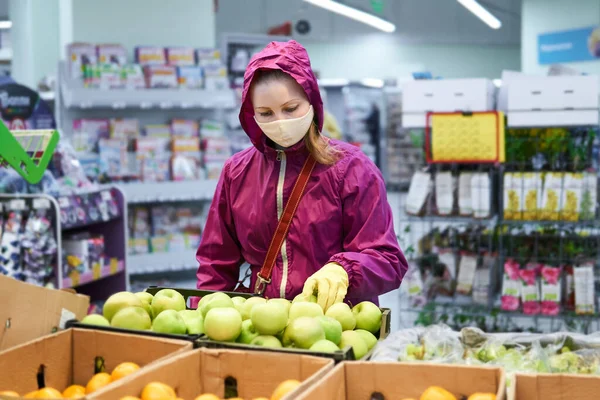 一名戴着自制口罩和防护手套的妇女在超级超级市场购买水果 — 图库照片