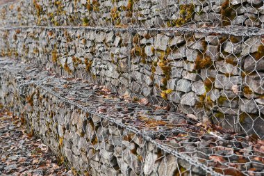 Granit kaya parçalarıyla altıgen tel örgü örülmüş gabion duvar perspektifi bulanıklaştırılmış.