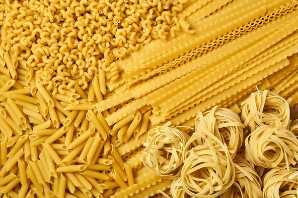 Goldener Hintergrund Verstreut Trockener Pasta Verschiedener Sorten — Stockfoto