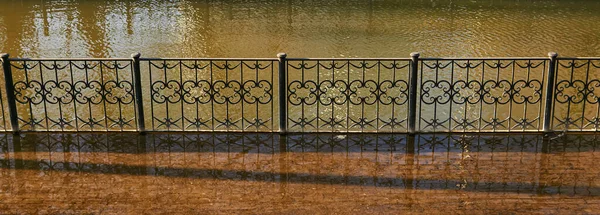 在春季洪水中 一条带有金属栏杆的城市运河的堤岸被洪水淹没 — 图库照片