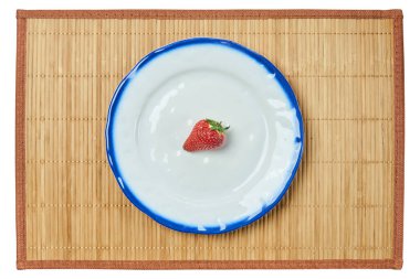 Çileğin yalnız meyvesi, beyaz bir tabakta, mavi bir...