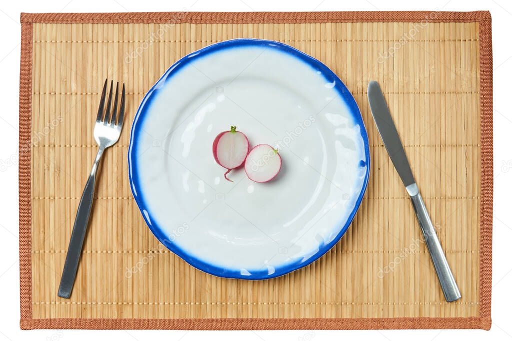 lone halved red radish lies on a plate, next to a knife and fork