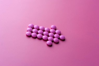 Pembe hapların yakın çekimi pembe bir yüzeye uzanıyor.