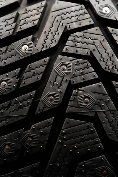 Studded car tire stands on a black background — Stock Photo, Image