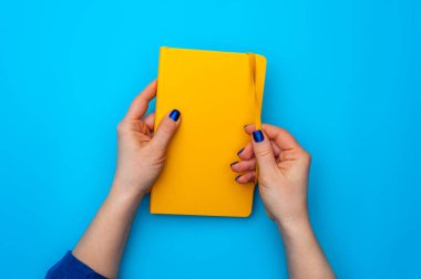 Güzel kadın elleri sarı bir günlükte yatıyor.