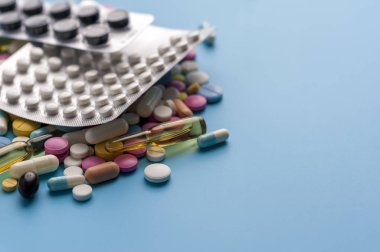 Blisters of pills and different capsules on blue background