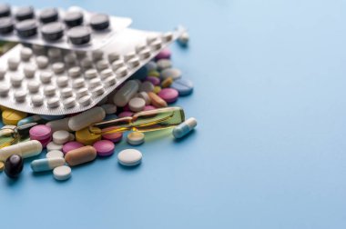 Blisters of pills and different capsules on blue background