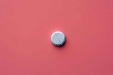 Close-up of one pill lies on a pink surface