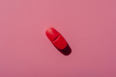 Close-up of one pill lies on a pink surface