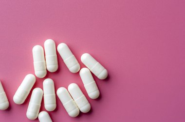Close-up of white pills lie on a pink surface