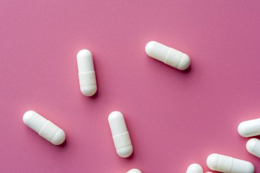 Close-up of white pills lie on a pink surface