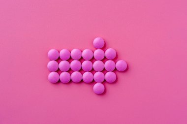 Pembe hapların yakın çekimi pembe bir yüzeye uzanıyor.