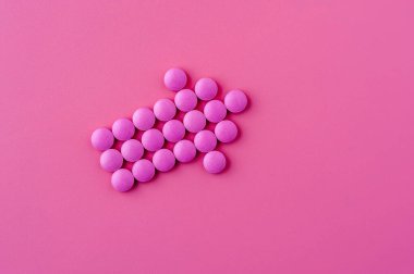 Pembe hapların yakın çekimi pembe bir yüzeye uzanıyor.