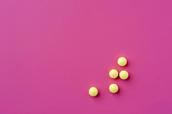 Primer plano de las píldoras amarillas se encuentran en una superficie rosa — Foto de Stock