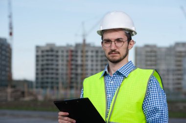 Planlı Yeşil Yelekli Genç Mühendis Portresi